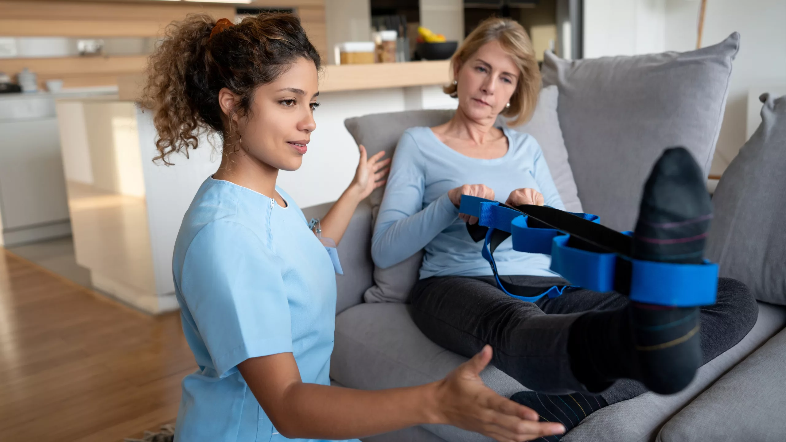 Mobile physiotherapy. Physiotherapist offering home visit, lady stretching on counch.