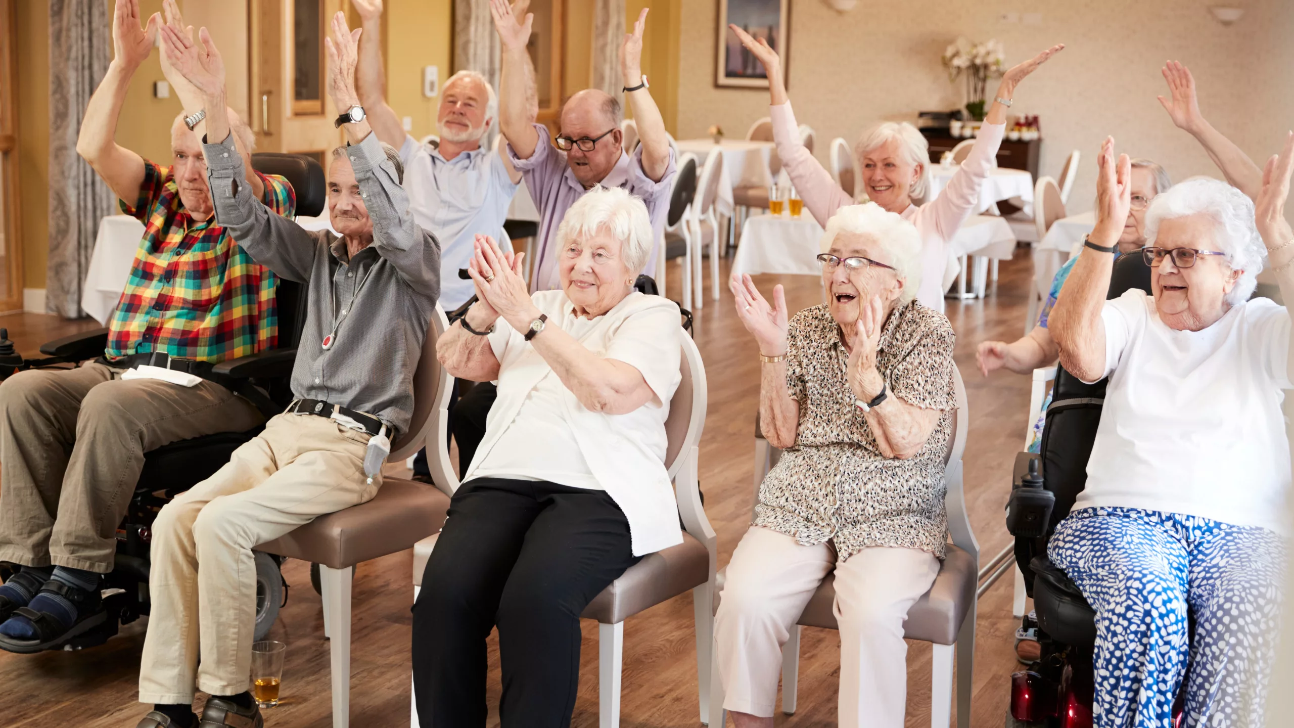 Older people doing chair based exercise class in retirement home. Celebrating senior fitness and health